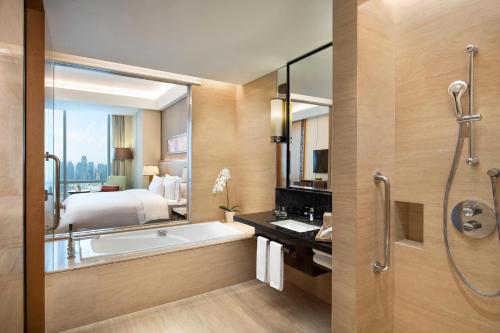 uma casa de banho com uma banheira, uma cama e um chuveiro em The Westin Jakarta em Jacarta