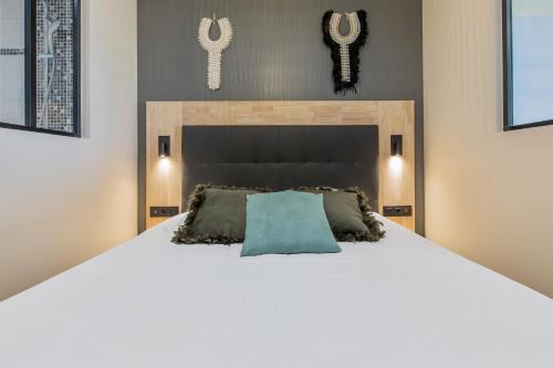 a bedroom with a large white bed with a blue pillow at Zen et Summer Zen coursive naturiste in Cap d'Agde