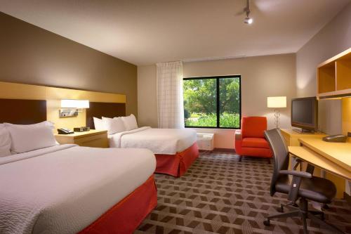 a hotel room with two beds and a desk at TownePlace Suites Omaha West in Omaha