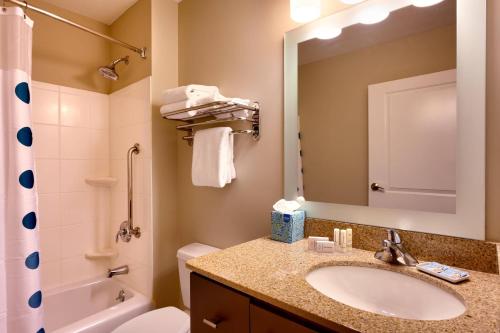 a bathroom with a sink and a toilet and a mirror at TownePlace Suites Omaha West in Omaha
