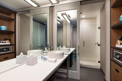 a bathroom with two sinks and two mirrors at Aloft Seattle Sea-Tac Airport in SeaTac