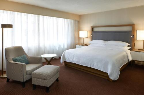 a hotel room with a large bed and a chair at Sheraton Ottawa Hotel in Ottawa