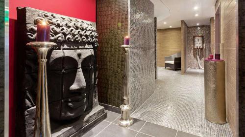 een badkamer met een gezicht op de muur met twee kaarsen bij Ax Hôtel Spa & Restaurant in Chorges