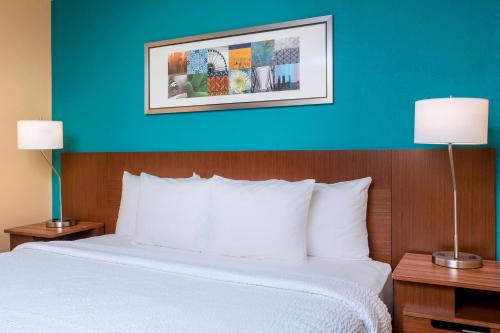 Fairfield Inn & Suites Victoria في فيكتوريا: سرير في غرفة فندق بجدار ازرق