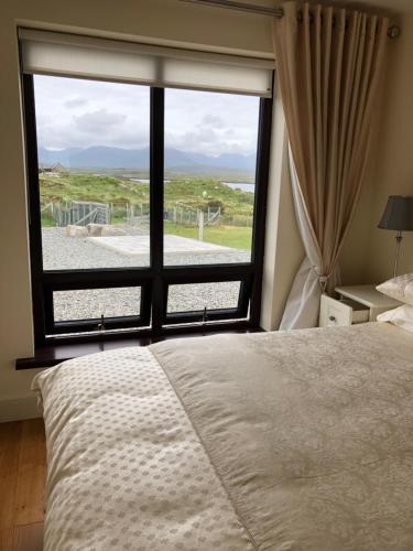 a bedroom with a large window with a view of the beach at Apartment at Island Cottage, Inishnee, Roundstone in Galway