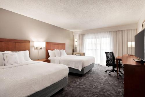 a hotel room with two beds and a desk at Courtyard by Marriott Tulsa Central in Tulsa