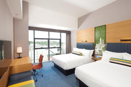 a hotel room with two beds and a desk at Aloft Dongguan Songshan Lake in Dongguan