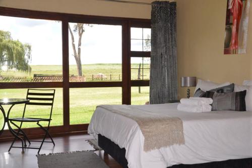 um quarto com uma cama, uma mesa e uma grande janela em ThakhuBrunfelsia em Secunda