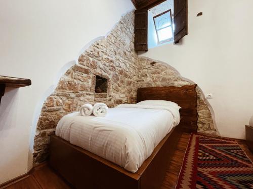a bed in a room with a stone wall at Tradita e Beratit in Berat