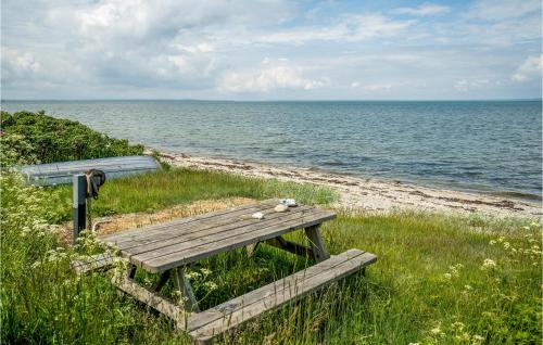 a wooden bench sitting on the side of a beach at Awesome Home In Bogense With Kitchen in Bogense