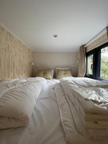 a large white bed sitting in a room at Ultiem ontspannen in compleet ingericht tiny house in bosrijke omgeving in Nunspeet
