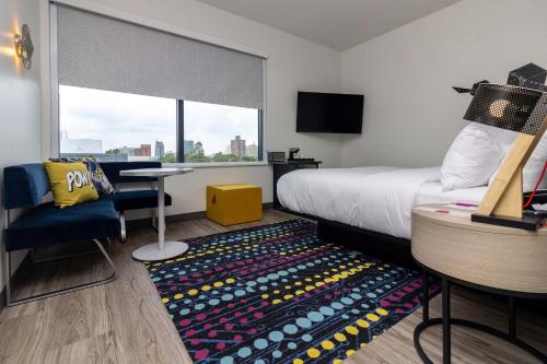 a hotel room with a bed and a table and a window at Aloft St. Louis Cortex in Saint Louis