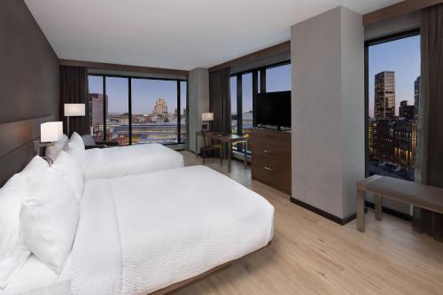 AC Hotel by Marriott Montreal Downtown في مونتريال: غرفة نوم بسرير ابيض ونوافذ كبيرة