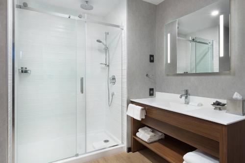 AC Hotel by Marriott Montreal Downtown في مونتريال: حمام مع دش ومغسلة ومرآة