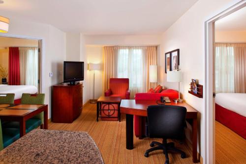 a hotel room with a desk and a bedroom at Residence Inn by Marriott Covington Northshore in Covington