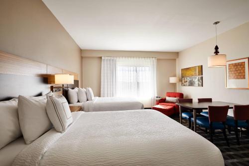 TownePlace Suites by Marriott St. Louis O'Fallon في أوفالون: غرفة فندقية بسريرين وطاولة وكراسي