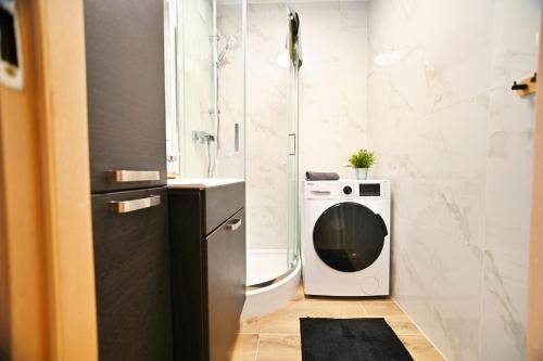 a bathroom with a shower and a washing machine at Horyzont by 3City Rentals in Gdynia