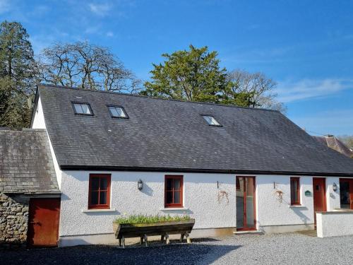 a white house with a bench in front of it at Kestrel Farmhouse in Llandovery