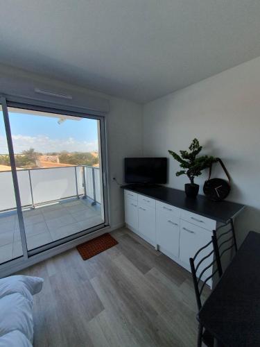 une chambre avec un lit et une grande fenêtre dans l'établissement appartement remblai saint hilaire de riez, à Saint-Hilaire-de-Riez