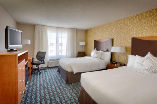 a hotel room with two beds and a flat screen tv at Fairfield Inn & Suites Salt Lake City Airport in Salt Lake City