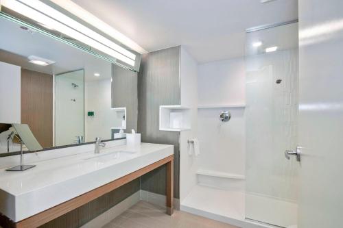 La salle de bains blanche est pourvue d'un lavabo et d'une douche. dans l'établissement Courtyard by Marriott Raleigh Cary/Parkside Town Commons, à Cary