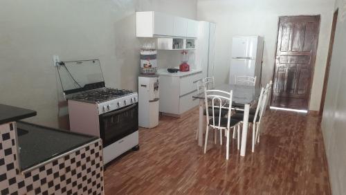 una cocina con electrodomésticos blancos, mesa y sillas en Sua Casa em Flecheiras, en Flecheiras
