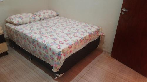 a bed in a room with a floral bedspread at Sua Casa em Flecheiras in Flecheiras