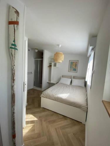 ein weißes Schlafzimmer mit einem Bett und einem Flur in der Unterkunft Studio au calme St Marc sur Mer in Saint-Nazaire