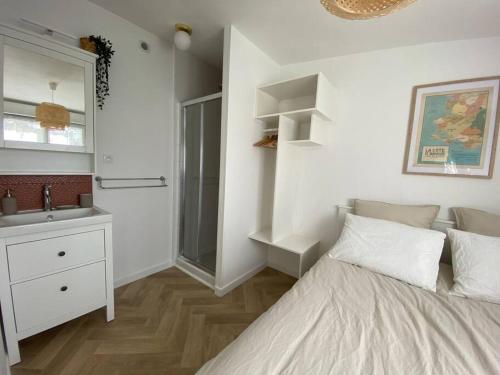 Schlafzimmer mit einem Bett, einem Waschbecken und einem Spiegel in der Unterkunft Studio au calme St Marc sur Mer in Saint-Nazaire