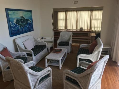 a living room with chairs and a piano at La Mer, a beautiful beachfront home in Sandbaai in Hermanus