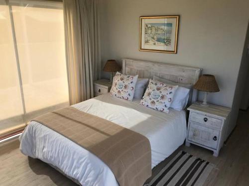 a bedroom with a white bed with pillows and a window at La Mer, a beautiful beachfront home in Sandbaai in Hermanus