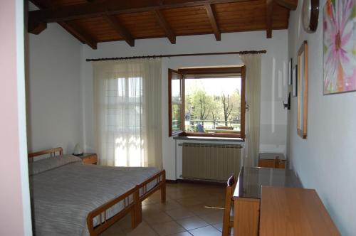 um quarto com uma cama, uma janela e uma mesa em B&B Il Gufetto em Viverone
