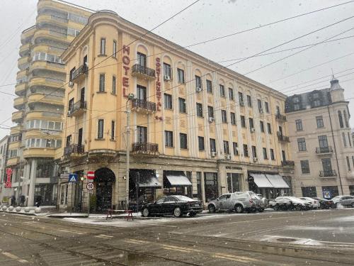 un grand bâtiment jaune avec des voitures garées devant lui dans l'établissement Hotel Continental, à Iaşi