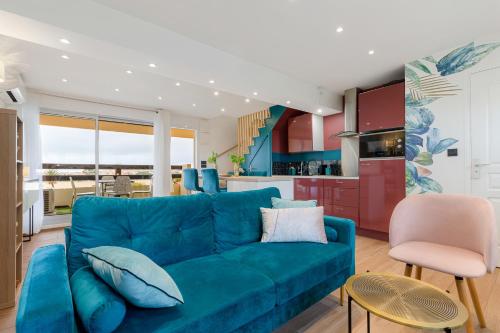 un salon avec un canapé bleu et une cuisine dans l'établissement Le duplex village naturiste vue mer, au Cap d'Agde