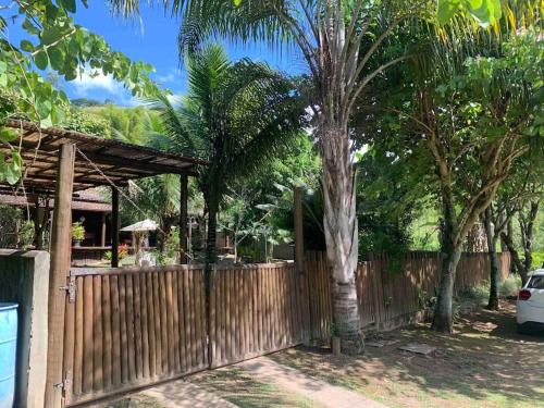 a wooden fence with a tree in front of a house at Casa Barra do Sana in Sana