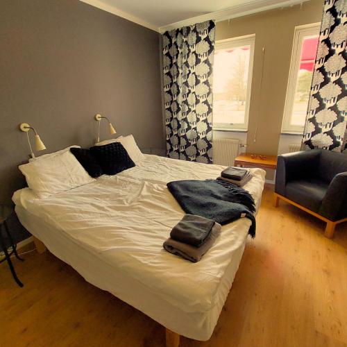ein Schlafzimmer mit einem weißen Bett mit einem Stuhl und einem Fenster in der Unterkunft Brevensgården 