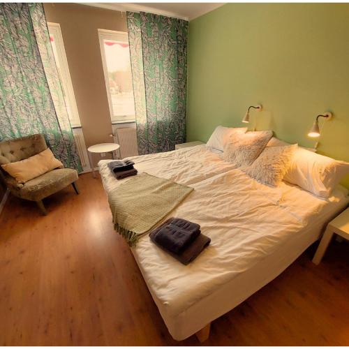ein Schlafzimmer mit einem großen weißen Bett und einem Stuhl in der Unterkunft Brevensgården 