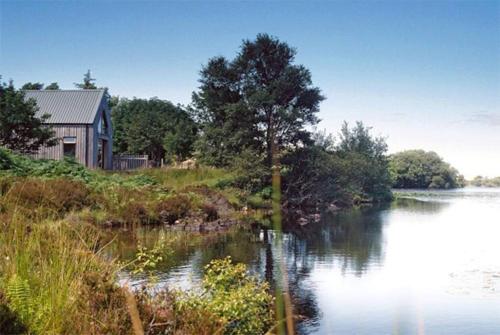 a house on a hill next to a lake at Blar na Leisg self catering Lodge 1 in Drumbeg