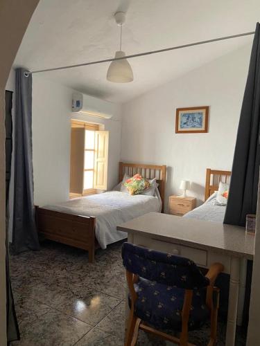 a bedroom with two beds and a table with a chair at Casa Alora in Alora