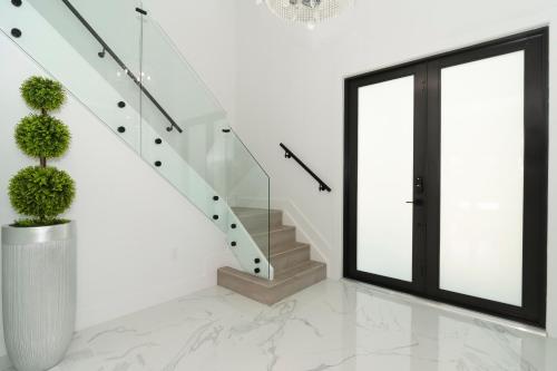a staircase in a white house with a glass door at The tropical paradise villa in Miami