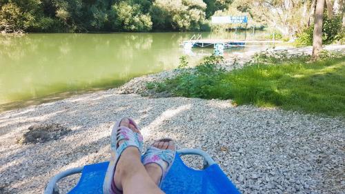 a person sitting on a chair near a body of water at Duna-Beach Apartman in Kimle