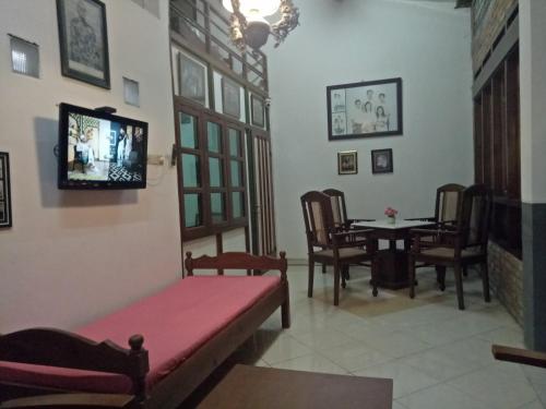 Una sala de estar con un sofá y un televisor en la pared. en Paviliun Omah Ndanu, en Yogyakarta