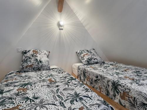 a bedroom with two beds and a lamp on the wall at Gite au gré de la Loire: massage, piscine et spa in Saint-Mathurin