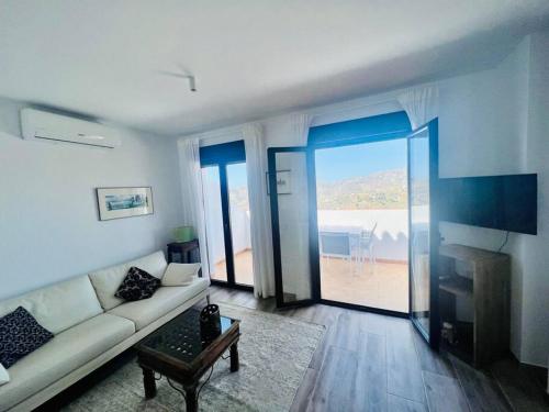 - un salon avec un canapé et une vue sur l'océan dans l'établissement Ático con increíbles vistas a las montañas y mar, à Frigiliana