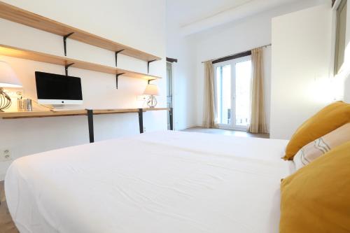 Habitación blanca con cama y TV en Bastide Magnolia - Les dépendances, Roussillon, en Roussillon