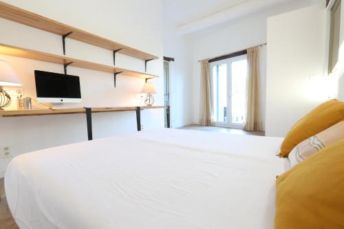 a white bedroom with a bed and a television at Bastide Magnolia - Les dépendances, Roussillon in Roussillon