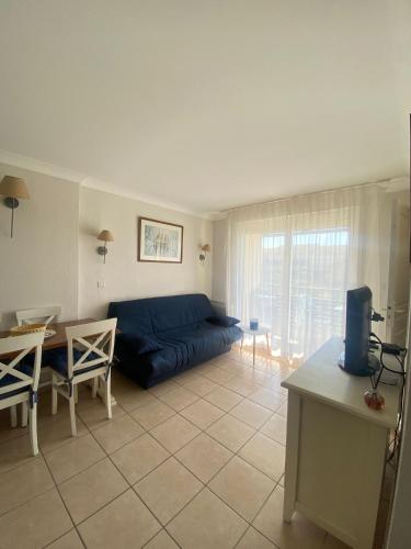 un salon avec un canapé bleu et une table dans l'établissement Appartement T2 lacanau ocean, à Lacanau-Océan