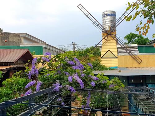 eine Windmühle auf einem Gebäude mit lila Blumen in der Unterkunft Boss cà phê & Homestay in Chi Lăng