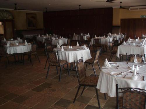una habitación llena de mesas y sillas con manteles blancos en F19 Ocean View Villas, en Port Edward