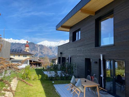 a house with a patio with mountains in the background at Black Forest Lodges - gehobene Ferienwohnungen mit Privatsaunas in Tulfes